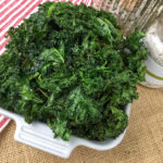 Crispy kale chips in a white serving dish.